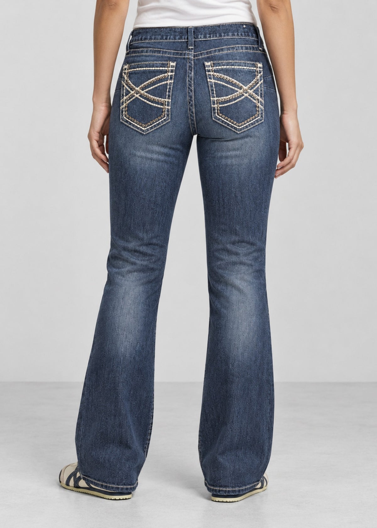 Blue wash bootcut jeans on female model, back view with embroidered patch pockets