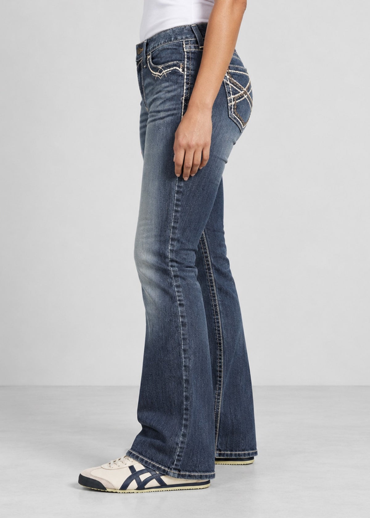 Blue wash bootcut jeans on female model, side view showing gentle flare
