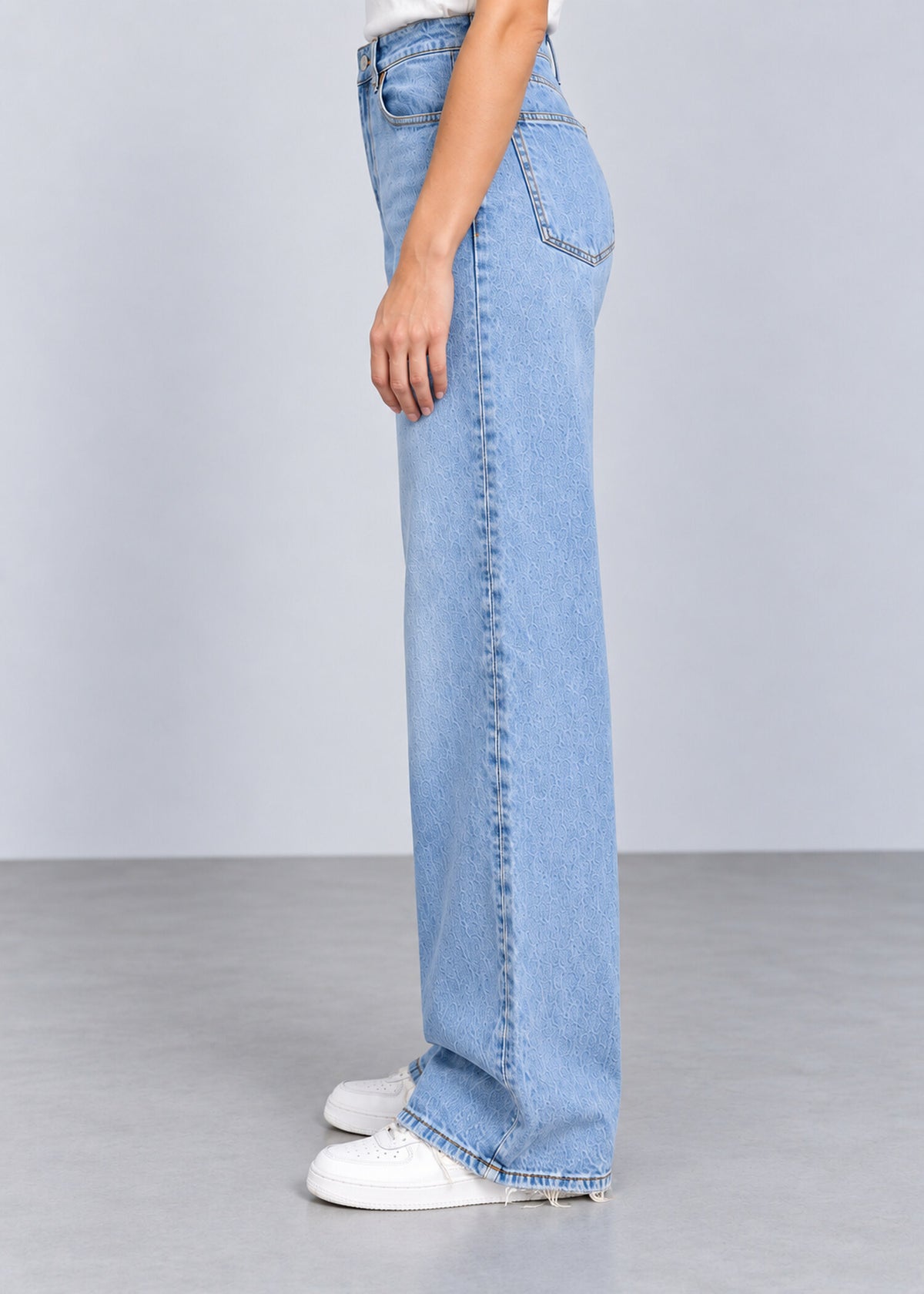 Light wash wide leg raw hem jeans on female model, side view
